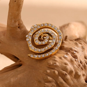 Detailed view of 18K gold plated spiral brooch with white diamonds on a rustic wood base