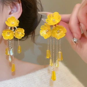 Details von gelben Blumen-Ohrringen mit goldenen Ketten und Kristall-Anhängern