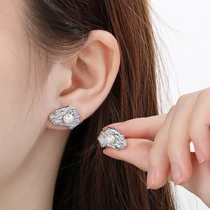 Detailed close-up of irregular textured silver earrings featuring elegant white pearls