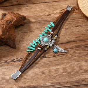 Detail of vintage leather bracelet with turquoise stones and leaf pendants on wood