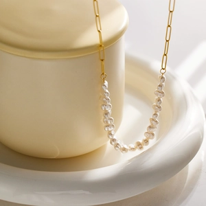 Detail view of a gold paperclip chain necklace featuring elegant baroque white pearls