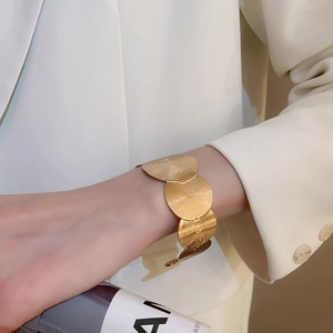 Detailed view of golden disc bracelet with spiral texture on a professional model