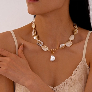 Detail of baroque pearl necklace with golden T-bar clasp and irregular pendant charm