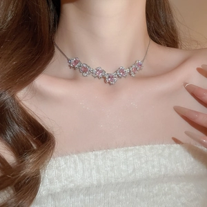 Close-up of elegant silver necklace with pink cubic zirconia flower pendant on a model