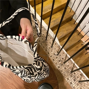 Detalle interior del bolso tote de cebra con bolsillo y cierre magnético de metal