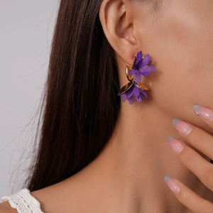 Detail of a purple fabric flower earring with gold leaf accent and hook fastener
