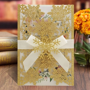 Golden glitter laser-cut snowflake wedding invitation with white ribbon bow and card