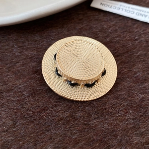 Detaillierte Nahaufnahme der goldenen Strohhut-Brosche mit Struktur und Seildetail