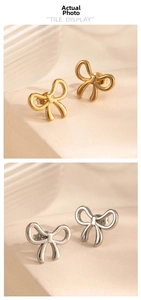 Detailed view of gold and silver polished stainless steel bow earrings on a textured stand