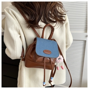 Mini zaino patchwork in pelle PU marrone e denim con ciondolo in peluche rosa su modella