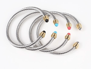 Detail of twisted cable steel open cuff bracelets with colorful beads and golden caps
