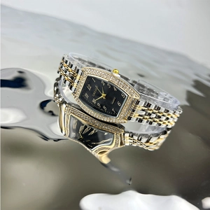 Macro detail of tonneau watch with emerald accents on reflective metallic surface