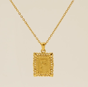 Macro d'un pendentif carré doré avec lettre F en relief et motifs de découpe exquis