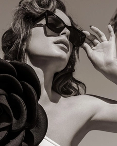 Close-up of 3D black rose floral detail on white luxury swimsuit with cat-eye sunglasses