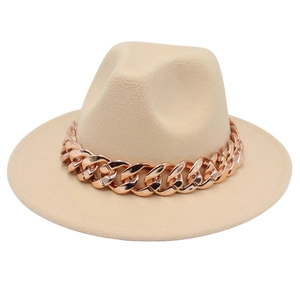 Detail of beige fedora hat featuring a chunky rose gold chain link decoration