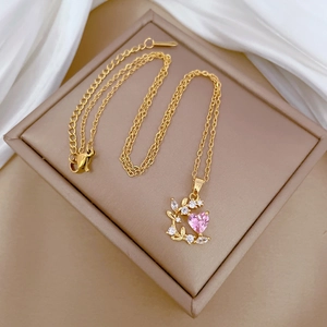 Detail of gold leaf pendant with pink heart-shaped stone and zircon on beige display
