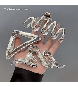 Detailed view of silver metal claw clips showing wave and triangle shapes with pearls