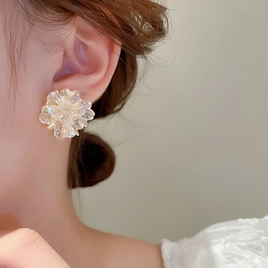 Detail of cream floral earring with rhinestones worn by a model in soft lighting