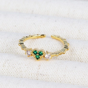 Close-up of 18K gold plated ring featuring three green emerald zircons on textured fabric