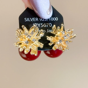 Close-up of silver needle pearl earrings with golden coral texture and red beads