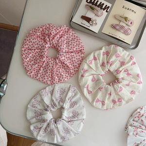 Floral cotton scrunchie set with bow patterns and pearl hair clips on a metal tray