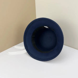 Detail view of navy wool felt bucket hat with white ribbon and 57 size label.