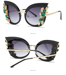 Detail of cat eye sunglasses with gold leaf accents and green rhinestones on black frame