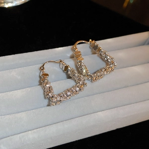 Macro detail of silver U-shaped earrings with micro-paved zircons on a display tray