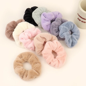 Set of soft fuzzy hair scrunchies in various pastel colors arranged on beige background