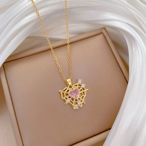 Detail of gold heart pendant with pink gemstone and crystals on beige jewelry box