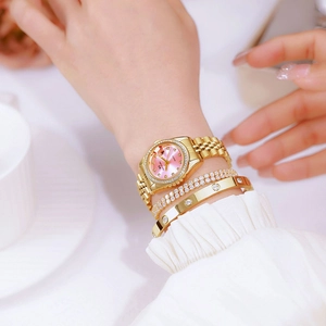 Elegant gold watch with pink dial and diamond bezel worn with matching bracelets
