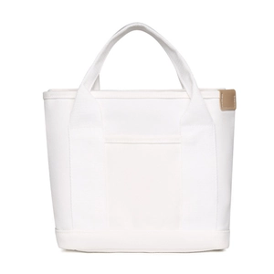 Detailed macro of white canvas tote bag with brown leather label on plain white background