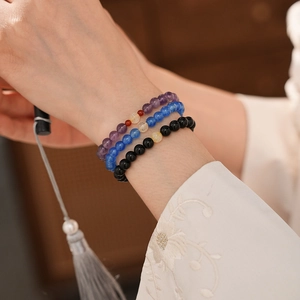 Detailed view of three-piece obsidian beaded bracelet set on woman wrist