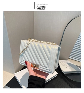 Detail of Aurora White crossbody bag featuring V-shaped quilting and golden chain