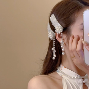 Close-up of elegant flower hair clips with pearl tassels worn by a model in soft lighting