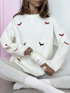 Detail of dachshund embroidery on a white crewneck knit sweater with drop shoulder design