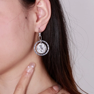 Detailed close-up of a silver coin portrait pendant earring on a female model