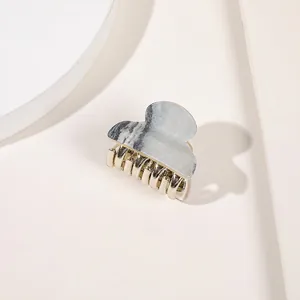 Macro detail of silver and gold metal hair claw clip with a spring mechanism