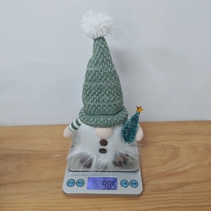 Detailed view of a green Christmas gnome ornament being weighed on a digital scale