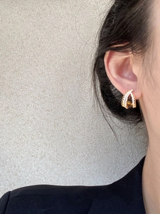 Close-up of elegant gold drop earring with tiger eye stone and zircons on model ear