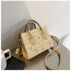 Detail of floral embroidery on a beige woven straw handbag with durable PU handles