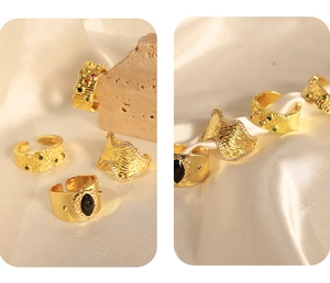 Dettaglio di anelli vintage dorati con texture martellata e diamanti su seta