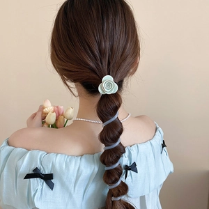 Détail d'un chouchou floral avec rose verte et élastique spirale sur une queue de cheval