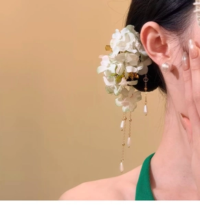 Detailed view of an elegant fabric flower hair clip with pearl tassels worn by a model