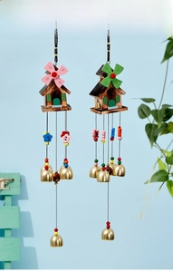 Detail of wooden windmill houses and golden bells on colorful resin wind chimes