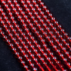 Macro detail of glossy red round glass beads arranged in rows for DIY jewelry making
