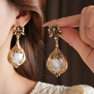 Gros plan de boucles d'oreilles vintage dorées avec résine perle et diamants brillants