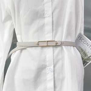 Slim light grey women's belt with cross-grain texture and gold geometric buckle on a shirt