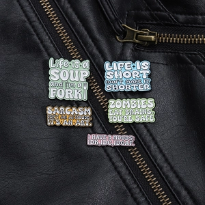 Detailed view of five colorful enamel funny pins pinned on a black leather jacket