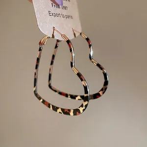 Rose gold heart hoop earrings with leopard print detail on a display card